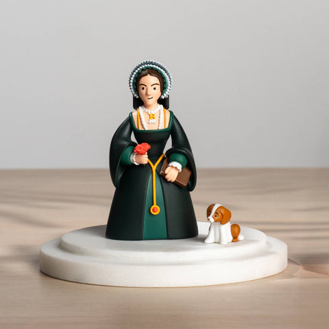 Figurine of Anne Boleyn in a green dress with a dog on a wooden surface