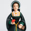Figurine of Anne Boleyn in historical attire holding a red flower on a light gray background