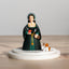 Figurine of Anne Boleyn in a green dress with a dog on a wooden surface